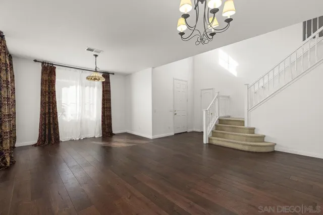 a view of an empty room with wooden floor and a chandelier