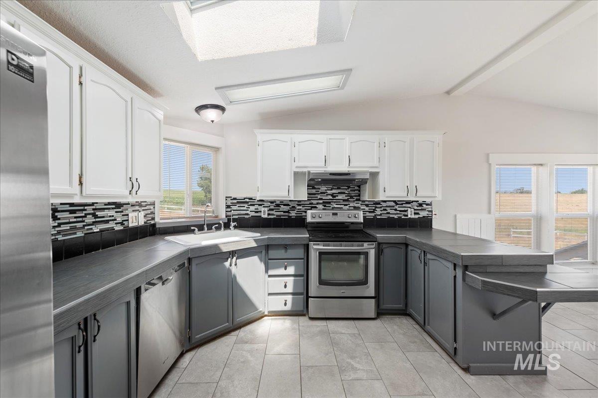 14490 Sand Hollow Road Caldwell, ID 83607 - Photo 39 of 50 Kitchen featuring a peninsula, appliances with stainless steel finishes, backsplash, and white cabinets
