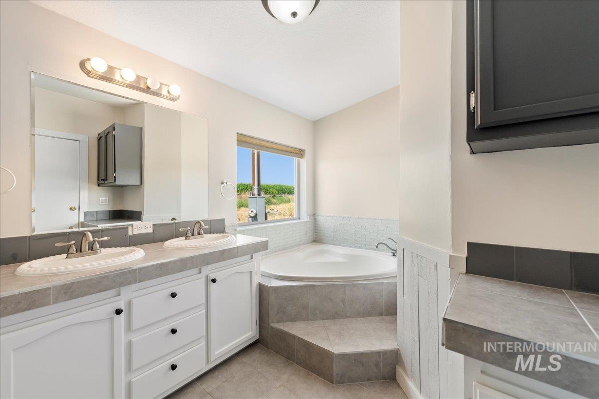 14490 Sand Hollow Road Caldwell, ID 83607 - Photo 41 of 50 Bathroom featuring double vanity, a large soaker bath tub, and tile patterned flooring