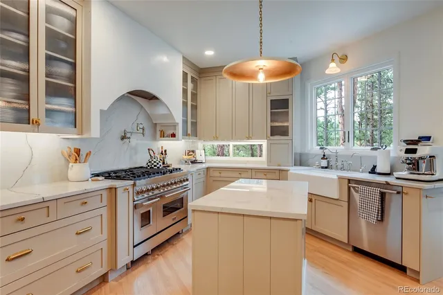 a kitchen with stainless steel appliances a stove a sink and white cabinets