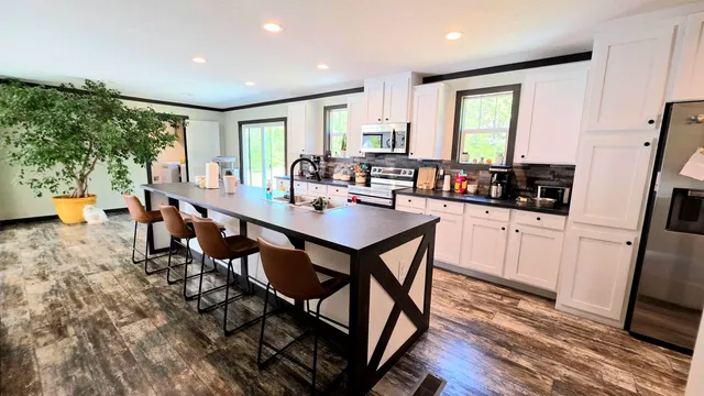 a kitchen with a dining table chairs and refrigerator