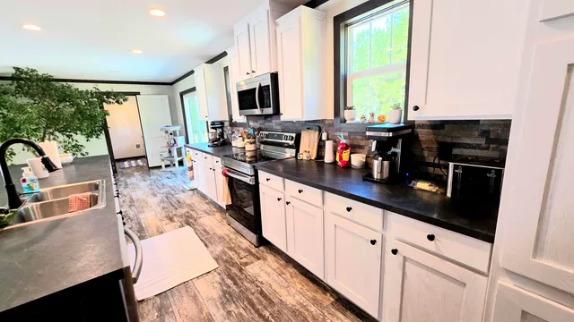 a kitchen with stainless steel appliances granite countertop a sink a stove and a wooden floors
