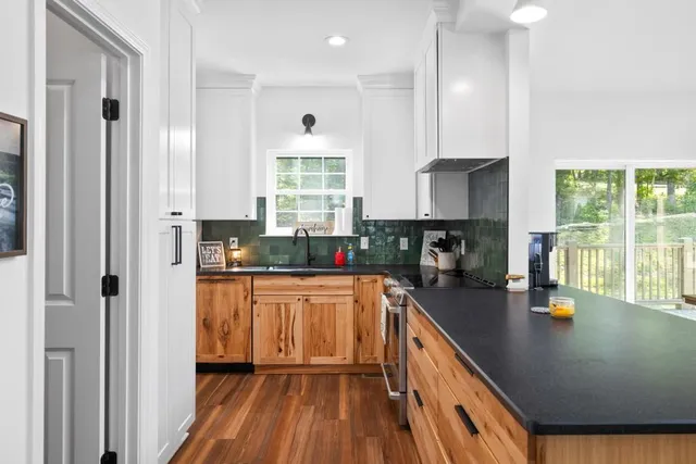 a kitchen with stainless steel appliances granite countertop hardwood floor sink stove dining table and chairs