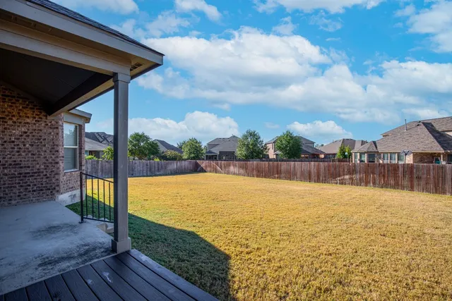 a view of a house with backyard and wooden fence