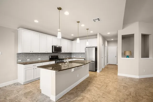a kitchen with kitchen island a sink and a stove top oven with wooden floor
