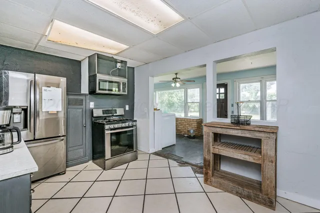a kitchen with granite countertop a refrigerator and a stove top oven
