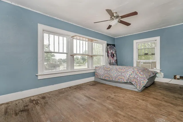 a bedroom with a large bed and two large window