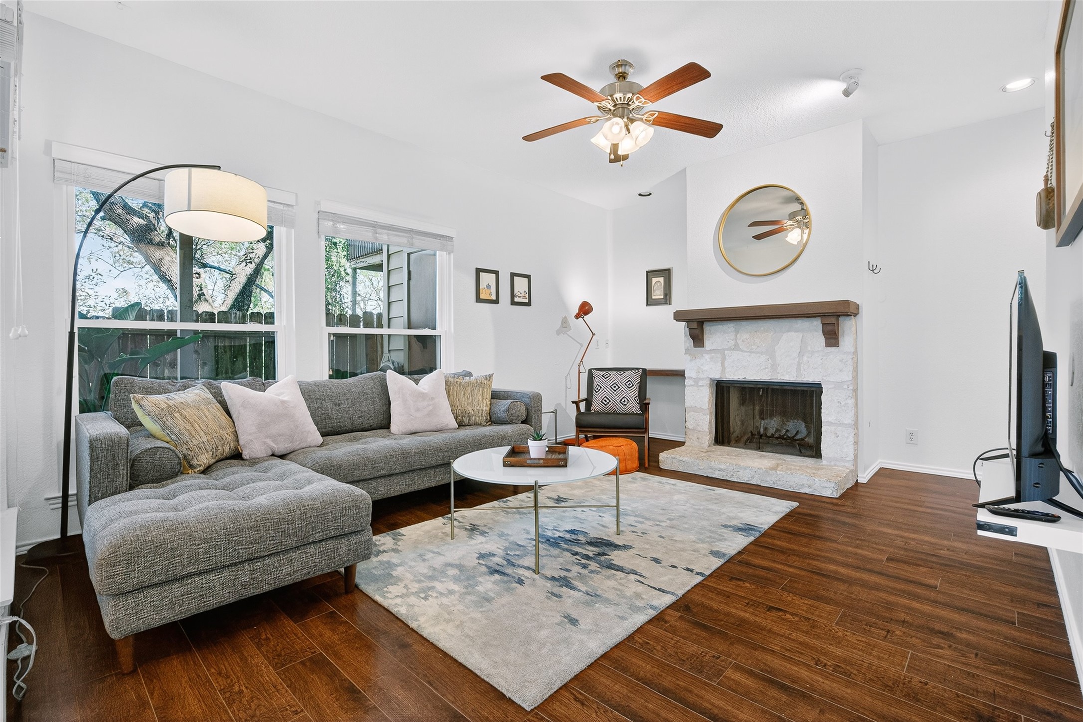 3809 Spicewood Springs Road, Unit 103 Austin, TX 78759 - Photo 3 of 39 Living room with wood-like floors, a stone fireplace, and a ceiling fan