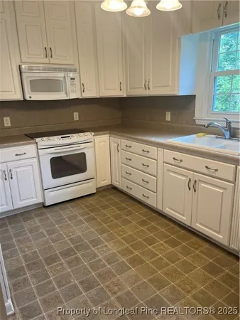 a kitchen with a stove a sink and white cabinets