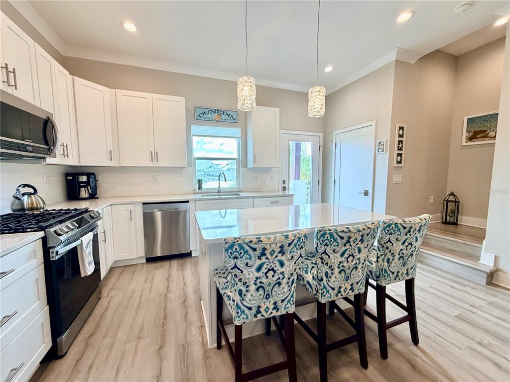 946 Highland Avenue Dunedin, FL 34698 - Photo 17 of 45 a kitchen with stainless steel appliances granite countertop a kitchen island hardwood floor sink stove dining table and chairs