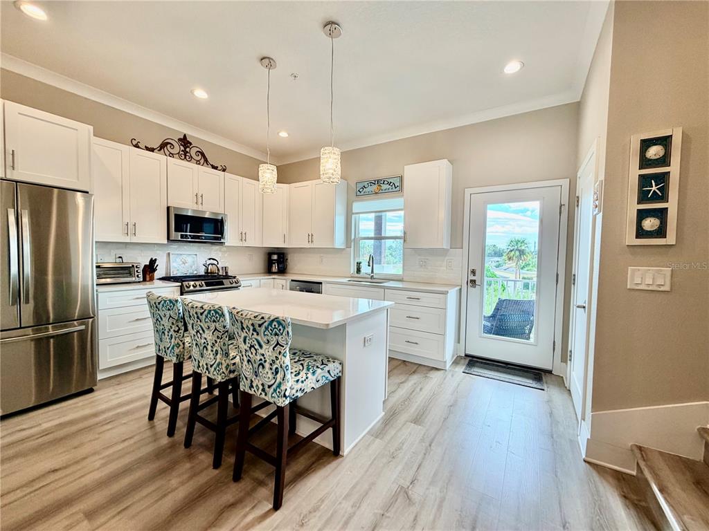 946 Highland Avenue Dunedin, FL 34698 - Photo 19 of 45 a kitchen with stainless steel appliances granite countertop a refrigerator a stove top oven a sink dishwasher and a dining table with wooden floor