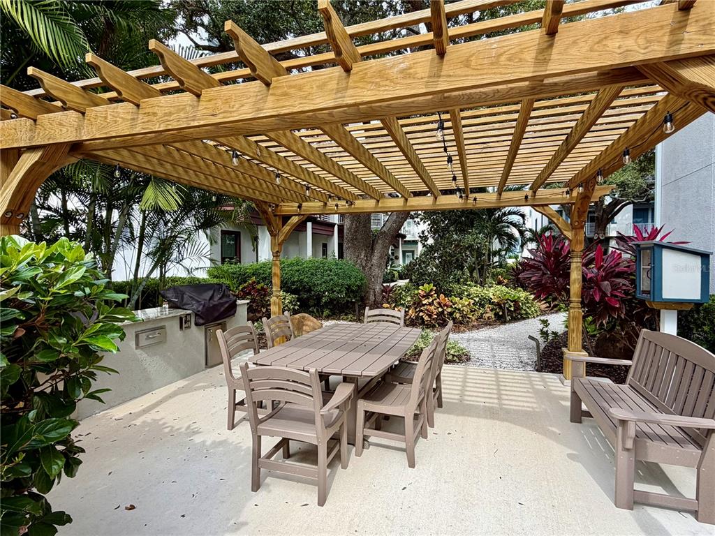 946 Highland Avenue Dunedin, FL 34698 - Photo 10 of 45 a view of a patio with table and chairs potted plants and palm trees