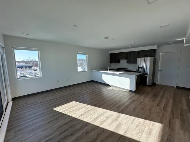 a living room with wooden floors and kitchen view