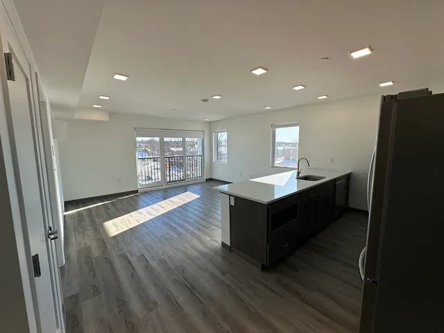 a living room with wooden floors and kitchen view