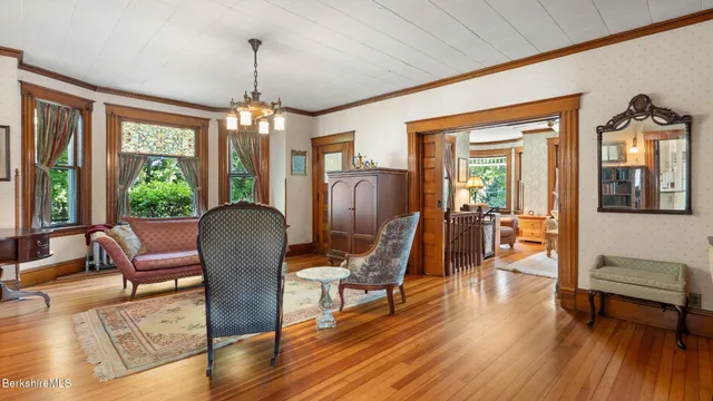 a dining room with wooden floor a chandelier a glass table and chairs