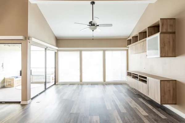a view of an empty room with wooden floor and a window