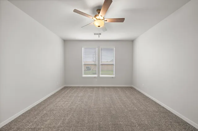 an empty room with a window and a ceiling fan