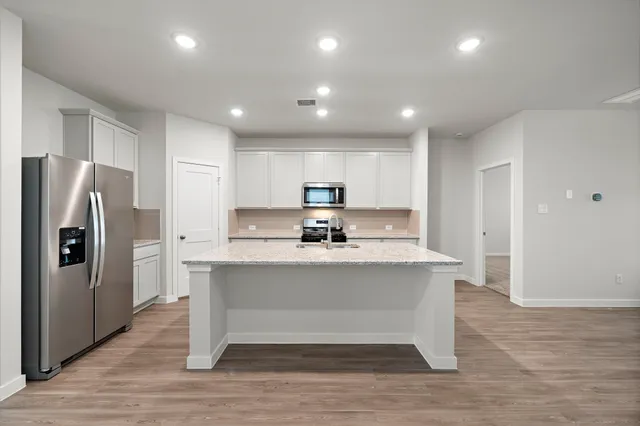 a view of kitchen with stainless steel appliances granite countertop refrigerator stove a sink dishwasher and a refrigerator with wooden floor