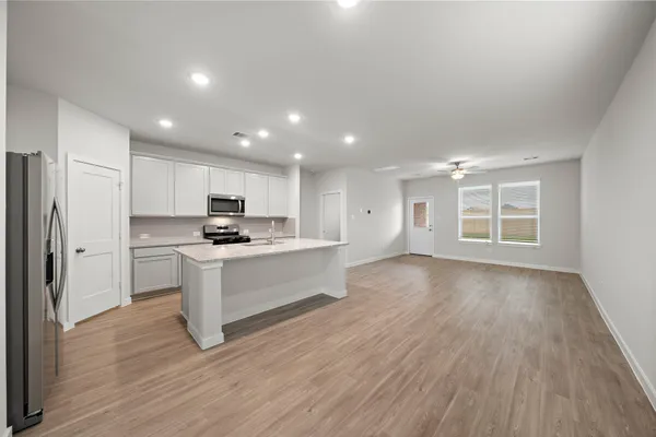 a view of kitchen with granite countertop refrigerator oven sink and white cabinets with wooden floor