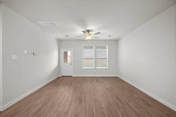 an empty room with wooden floor chandelier fan and windows