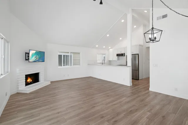 a view of empty room with wooden floor and fireplace