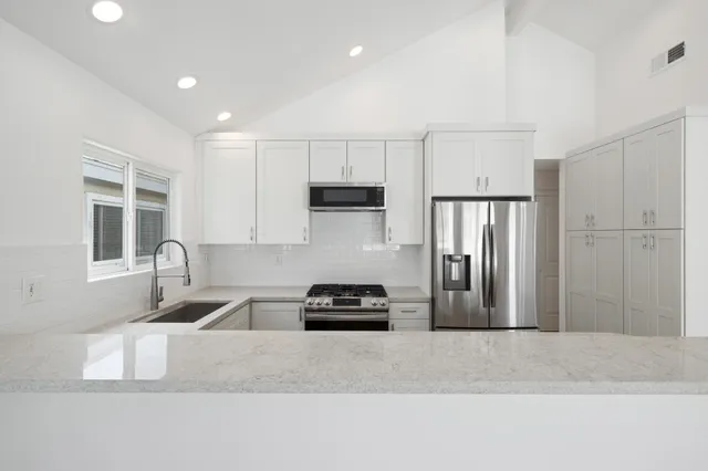 a kitchen with granite countertop a refrigerator and a stove top oven