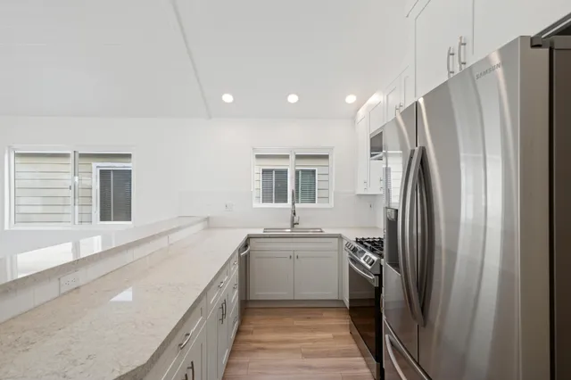 a kitchen with stainless steel appliances granite countertop a refrigerator a sink a stove and a refrigerator