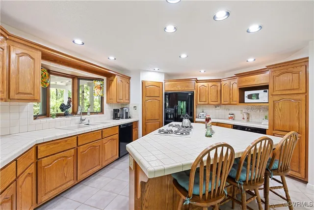 a kitchen with stainless steel appliances granite countertop a table chairs sink refrigerator and cabinets