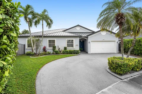 a front view of a house with a garden and palm trees