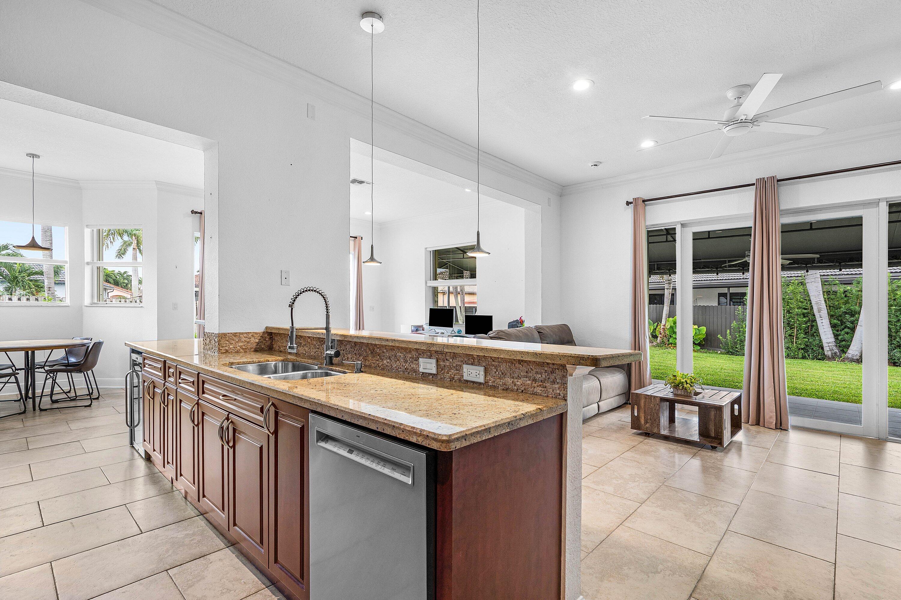 16852 Northwest 88th Path Miami Lakes, FL 33018 - Photo 11 of 34 a kitchen with kitchen island a sink dining table and chairs