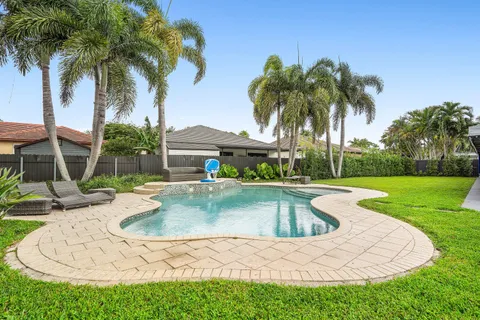 a view of a swimming pool with a garden and palm trees