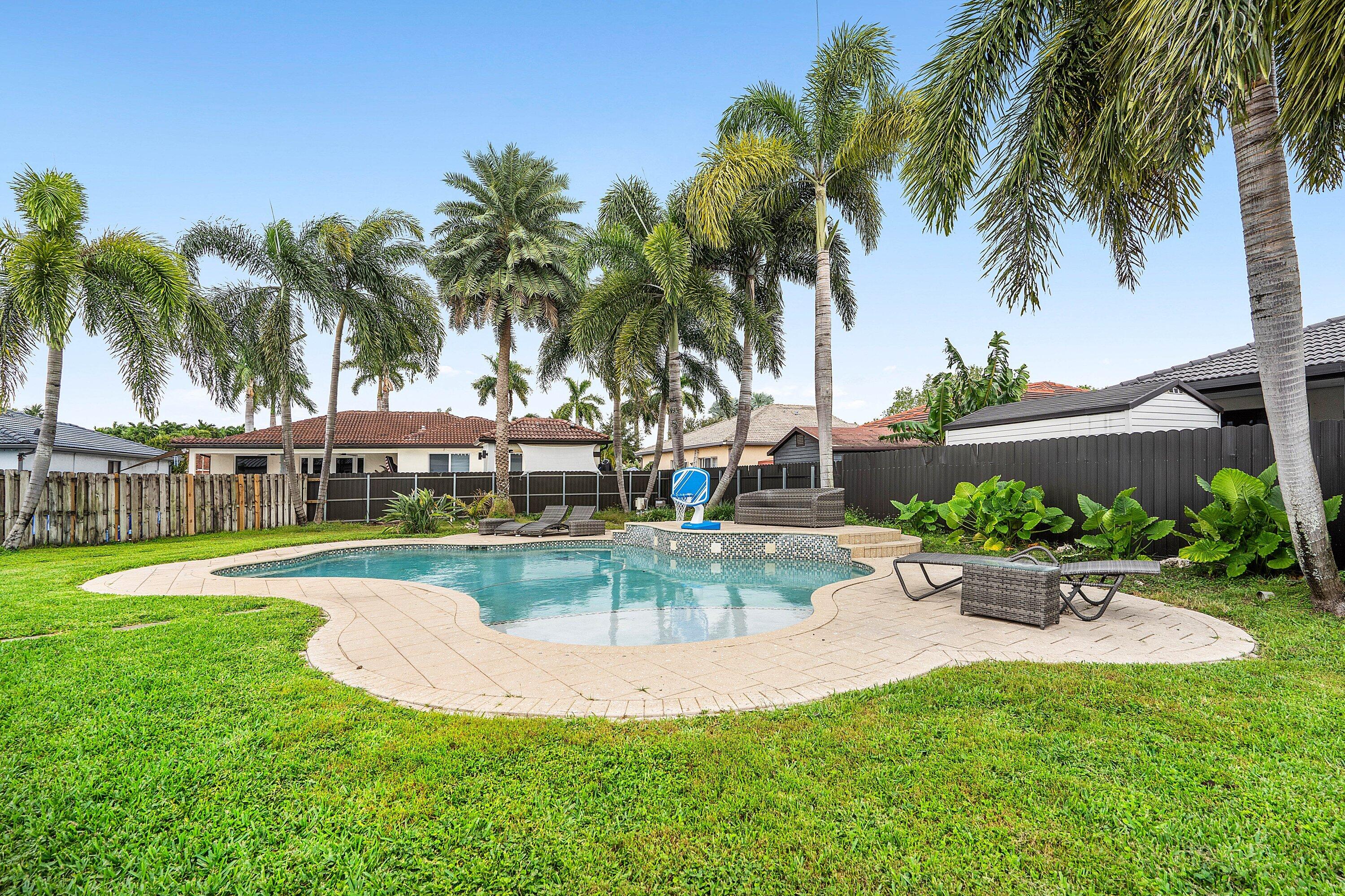16852 Northwest 88th Path Miami Lakes, FL 33018 - Photo 32 of 34 a view of a swimming pool with a garden and palm trees