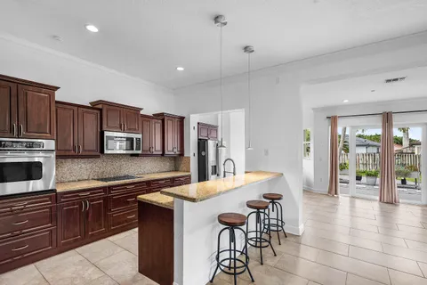 a kitchen with stainless steel appliances granite countertop a stove top oven a sink dishwasher a dining table and chairs with wooden floor