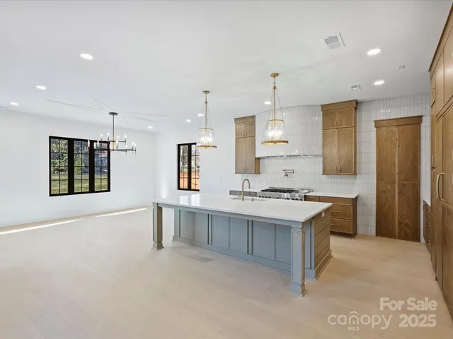 a large kitchen with kitchen island a sink stainless steel appliances and cabinets