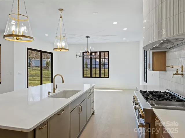 a kitchen with stainless steel appliances a sink a stove a dining table and chairs