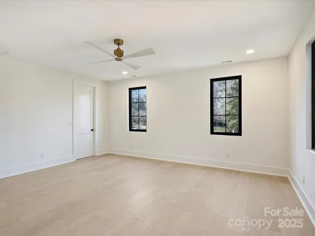 an empty room with windows and fan