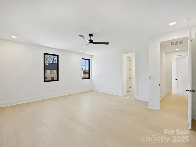 an empty room with windows and ceiling fan