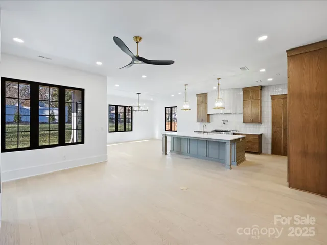 a large white kitchen with kitchen island a large counter top space a sink stainless steel appliances and cabinets