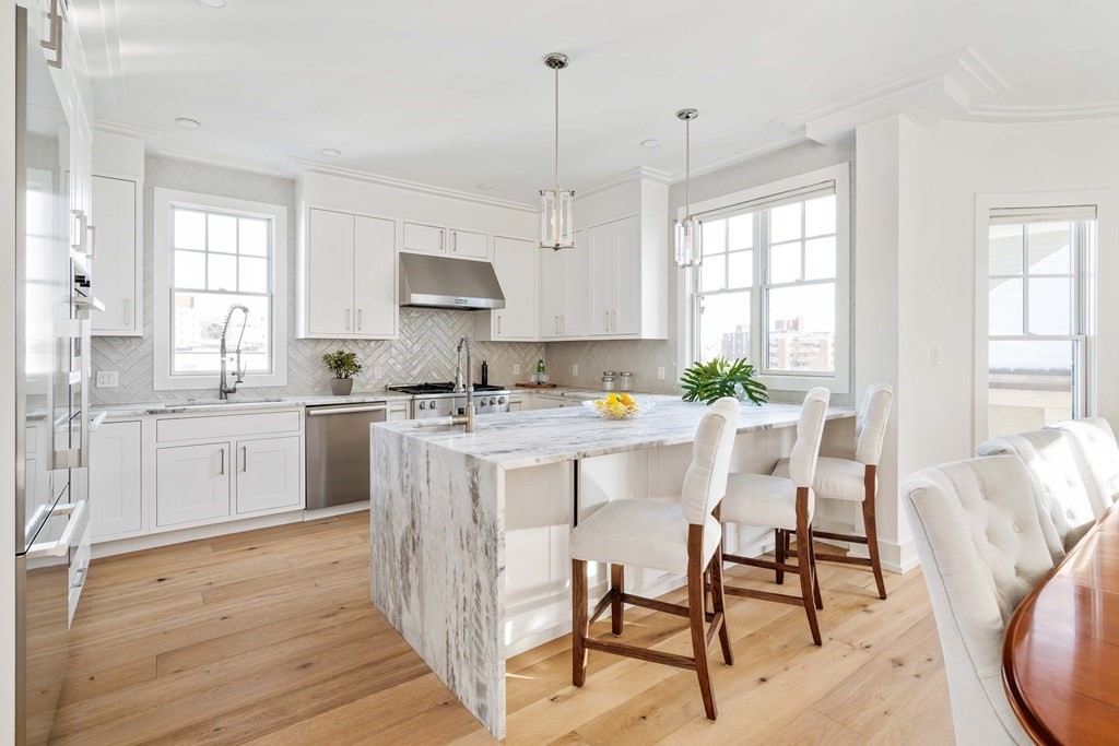 33 Summit Avenue, Unit 33 Brookline, MA 02446 - Photo 11 of 28 a kitchen with stainless steel appliances white cabinets a table and chairs in it