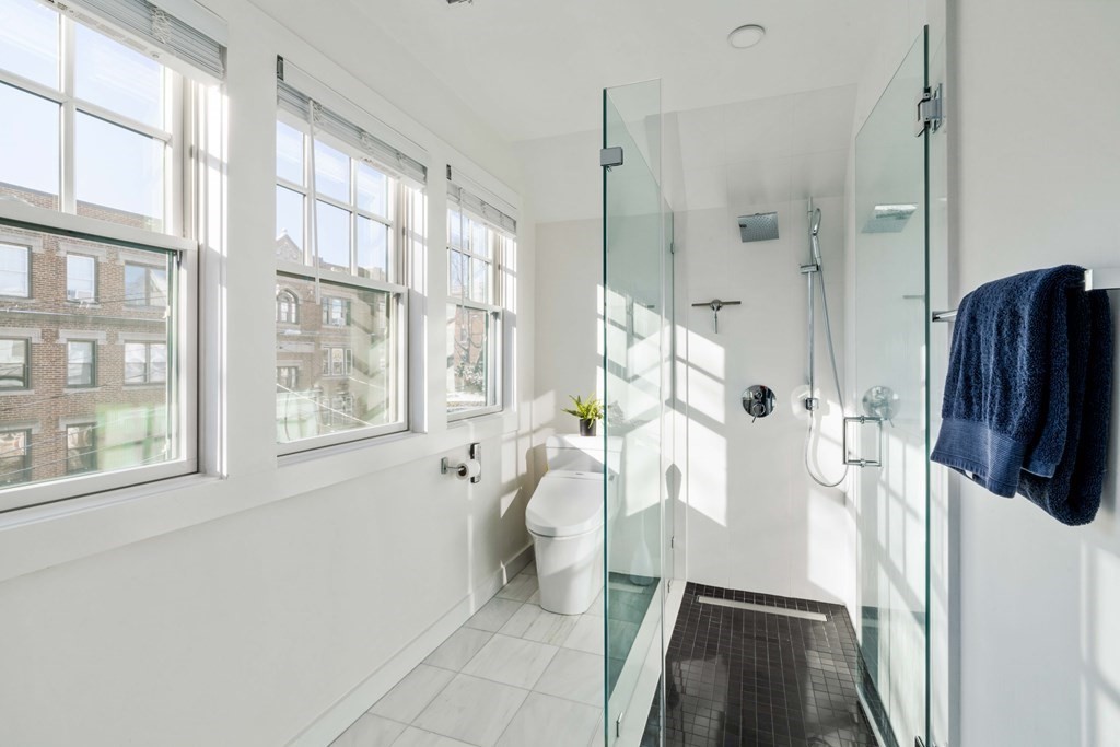 33 Summit Avenue, Unit 33 Brookline, MA 02446 - Photo 22 of 28 a bathroom with a shower a sink a toilet a window and a glass door