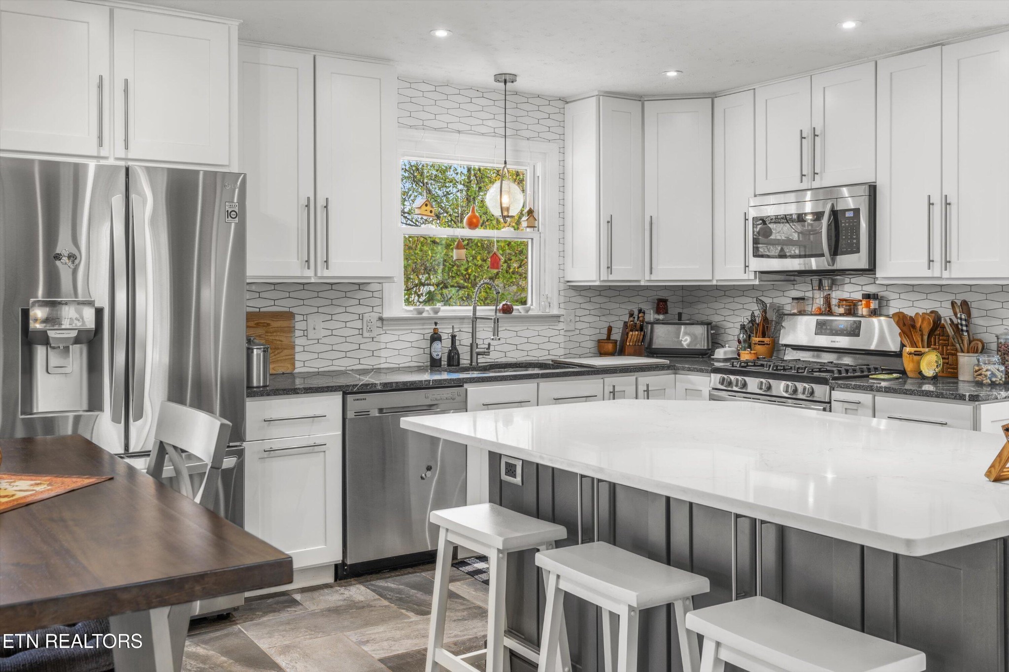 7919 North Forest Road Knoxville, TN 37909 - Photo 11 of 29 a kitchen with stainless steel appliances a table chairs sink refrigerator and cabinets
