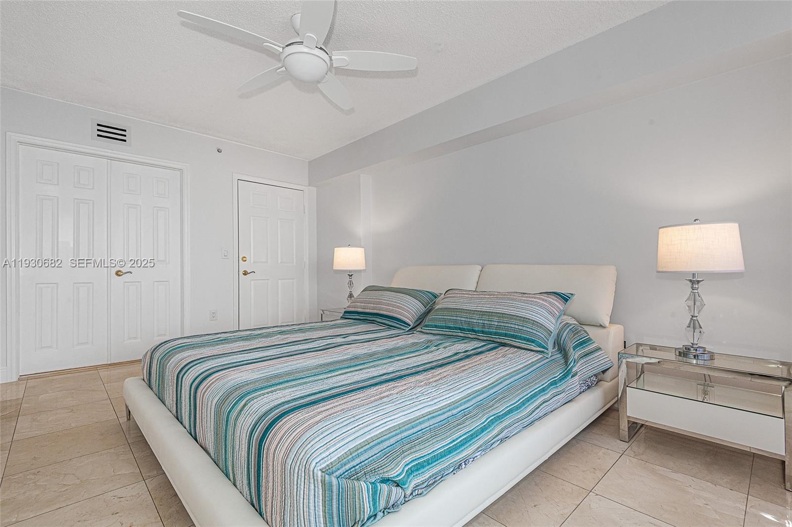 6301 Collins Avenue, Unit 1605 Miami Beach, FL 33141 - Photo 19 of 23 a spacious bedroom with a bed and a lamp