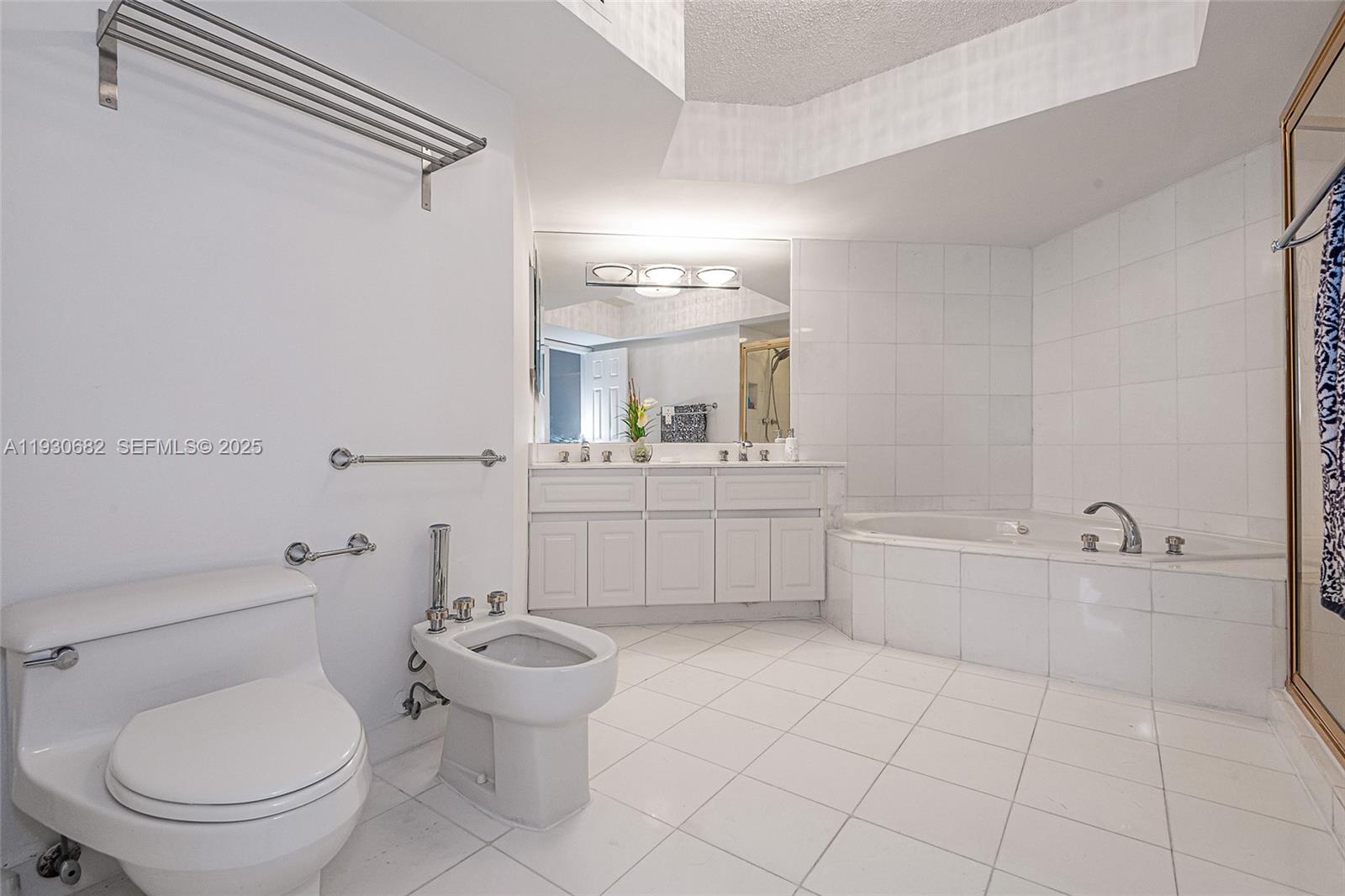 6301 Collins Avenue, Unit 1605 Miami Beach, FL 33141 - Photo 20 of 23 a bathroom with a toilet a sink a mirror and a bathtub