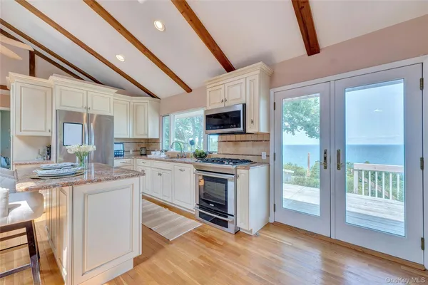 a kitchen with stainless steel appliances granite countertop a stove a sink dishwasher a refrigerator white cabinets and wooden floor