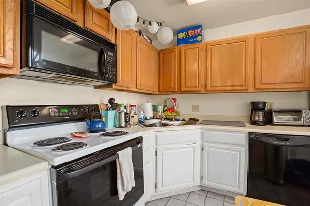 a kitchen with granite countertop a stove top oven a sink dishwasher and white cabinets with wooden floor
