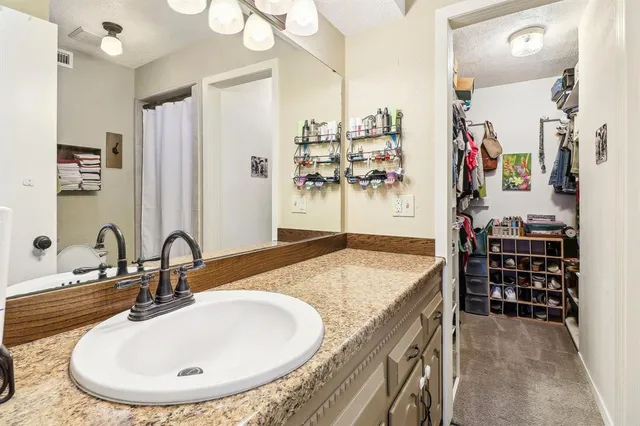 a bathroom with a granite countertop sink a mirror and shower