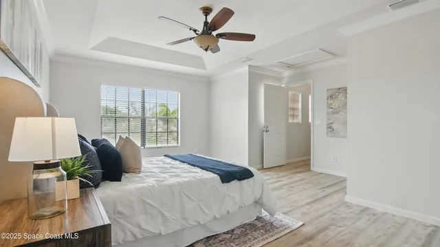 a bed sitting in a bedroom next to a window and a chandelier