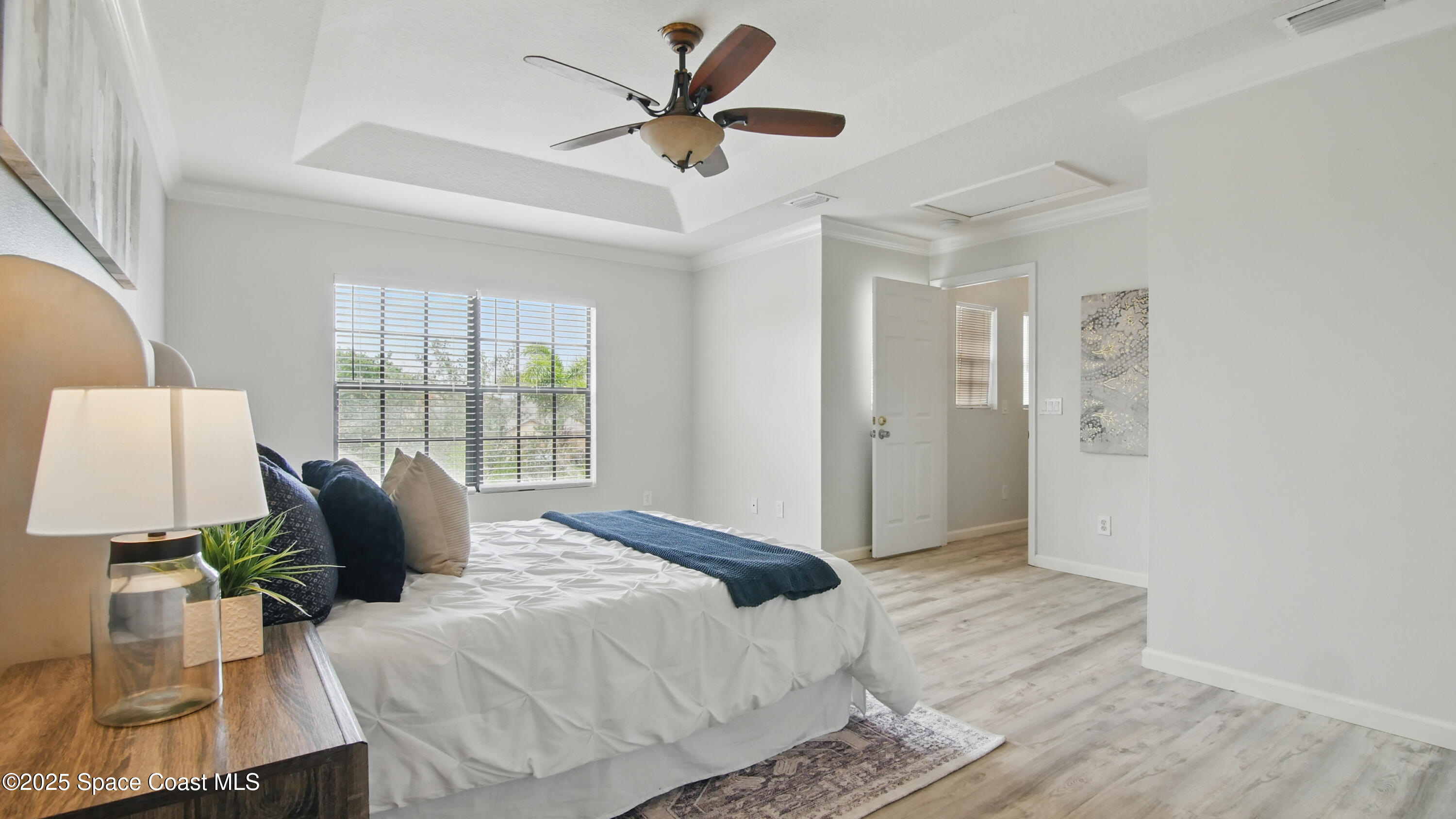 1160 Luminary Circle, Unit 105 Melbourne, FL 32901 - Photo 11 of 16 a bed sitting in a bedroom next to a window and a chandelier