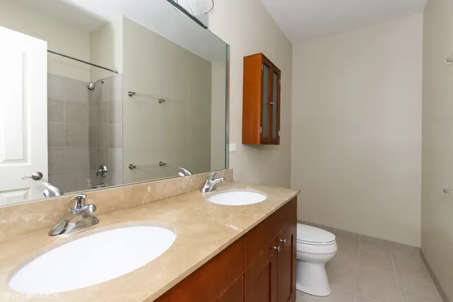 a bathroom with a granite countertop sink toilet and mirror