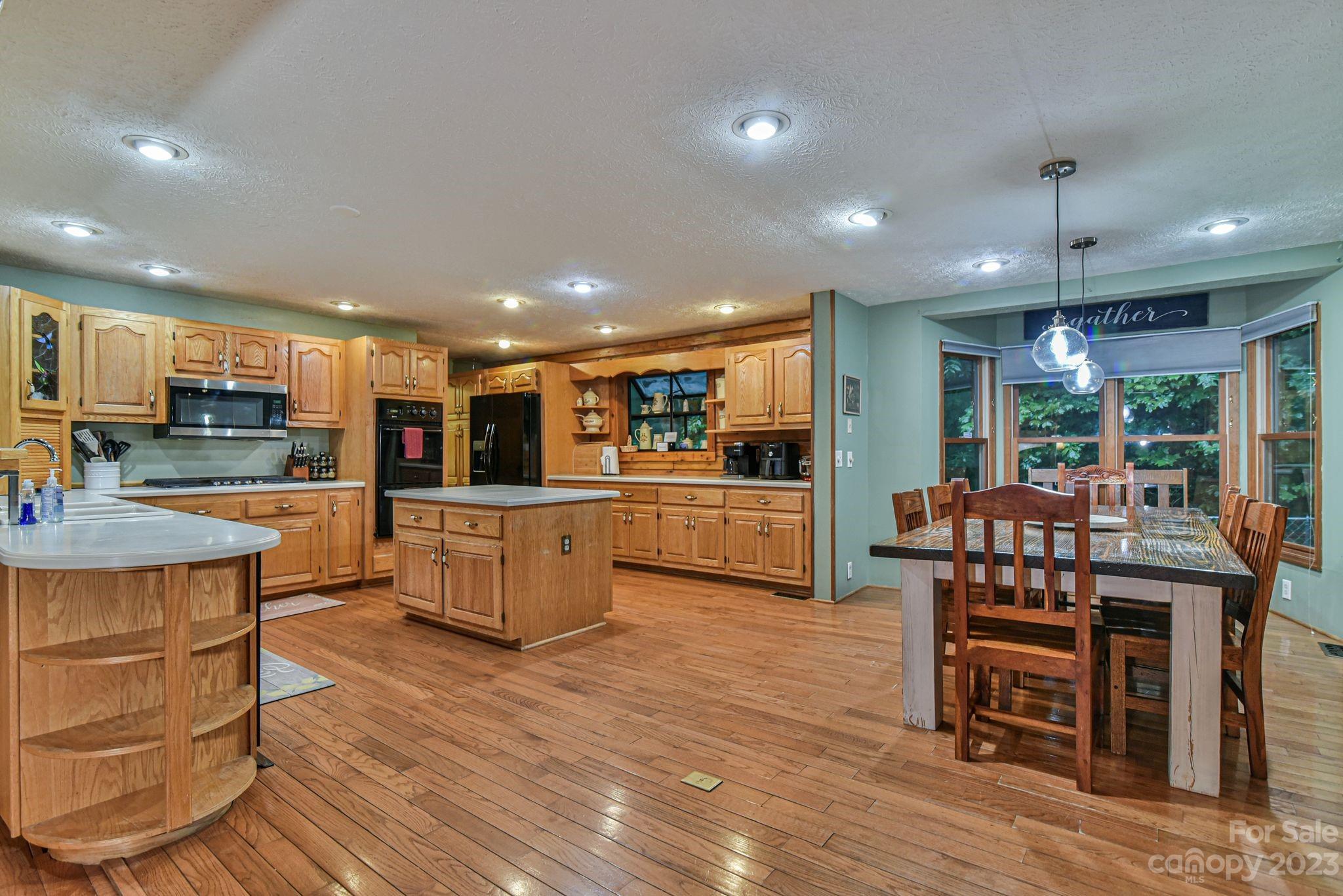 32 Magic Mountain Road Candler, NC 28715 - Photo 15 of 44 a kitchen with stainless steel appliances kitchen island granite countertop wooden floors and wooden cabinets